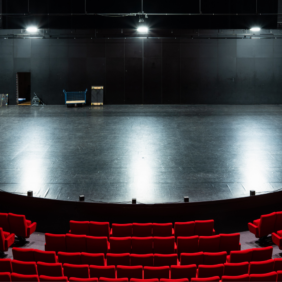 salle de théâtre avec des fauteuils rouges et une scène ouverte sur les coulisses