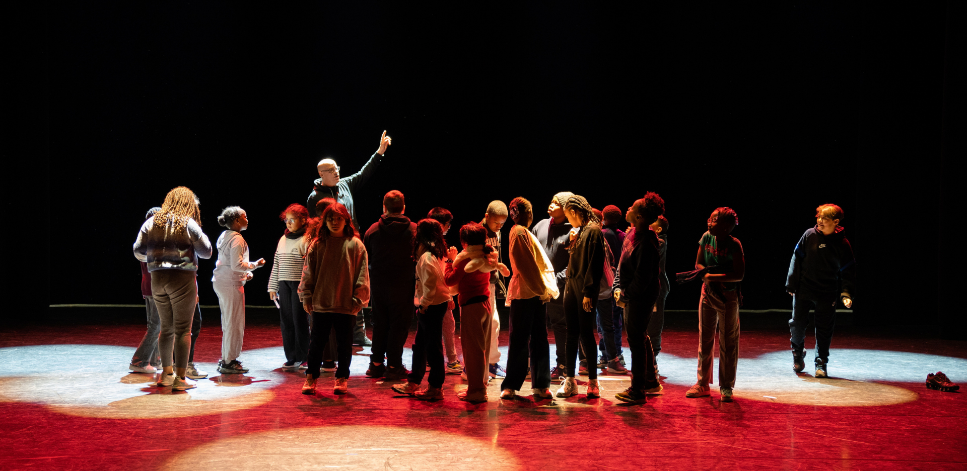 Un groupe d'enfants sur la scène d'un théâtre, en compagnie d'un technicien qui explique le fonctionnement des lumières